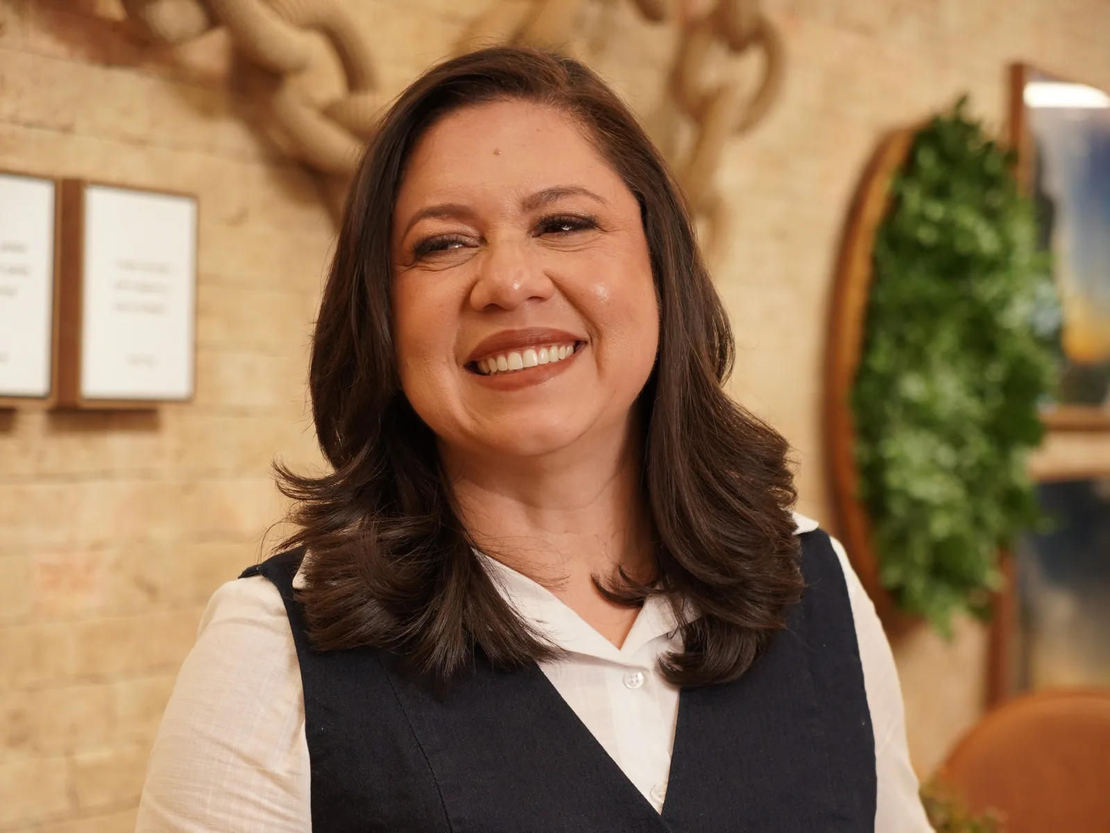 Dra. Priscila Araújo sentada à mesa da clínica, sorrindo